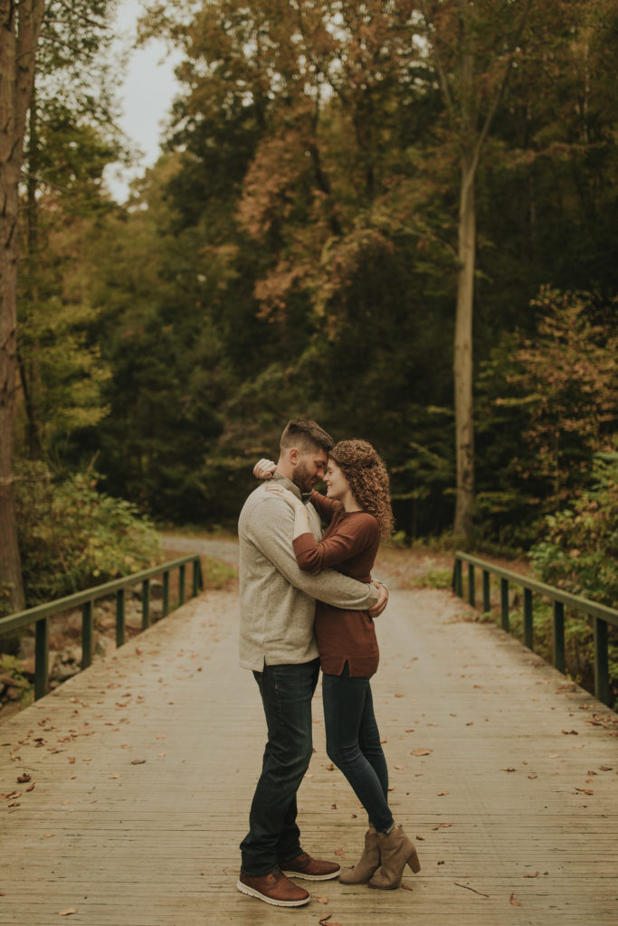 A couple kissing on a bridge in the middle of the woods in Pine Grove Pennsylvania