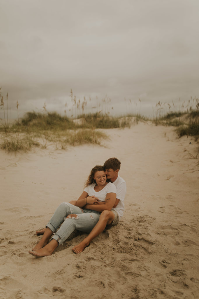 A north carolina couple sitting on the ocean isle beach during their engagement photoshoot