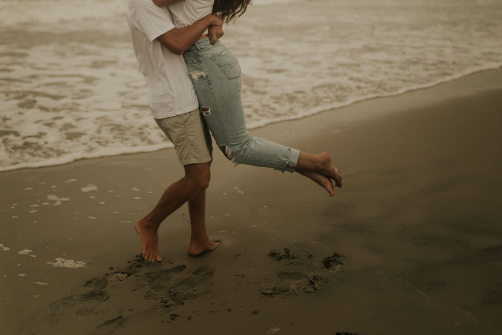 A north carolina couple playing on the ocean isle beach during their engagement photoshoot