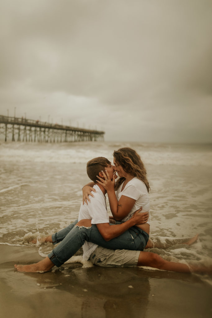 A north carolina couple kissing in the water at the ocean isle beach during their engagement photoshoot