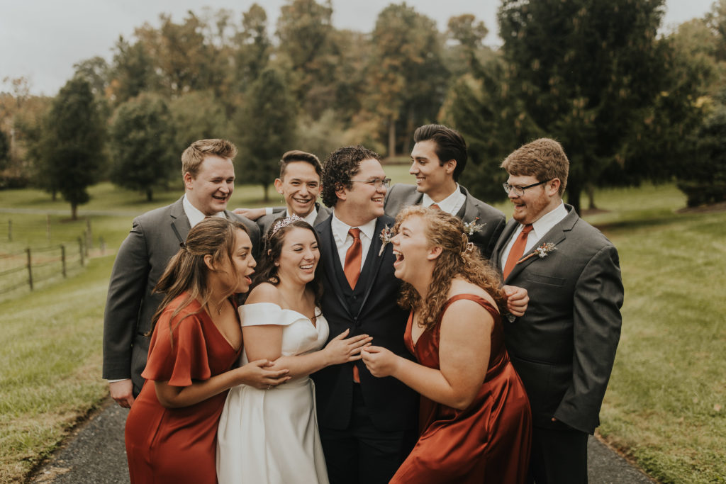 The wedding party dressed in terracotta, silk dresses with the groomsmen.