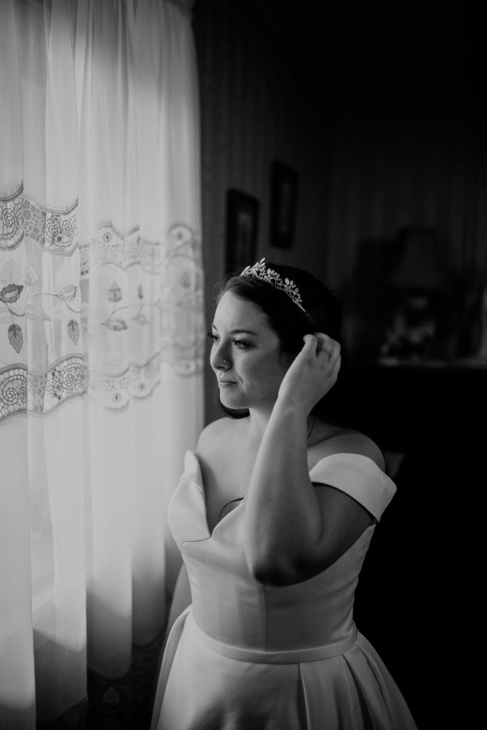 The bride looking out the window in her wedding dress waiting for the wedding ceremony to start.