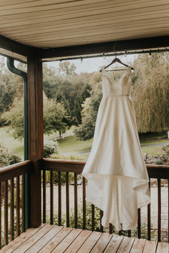 A brides wedding dress on her wedding day hanging at the wedding venue