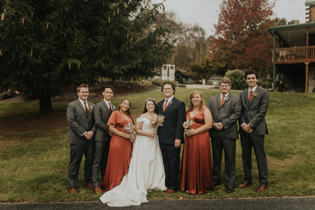The wedding party dressed in terracotta, silk dresses with the groomsmen.