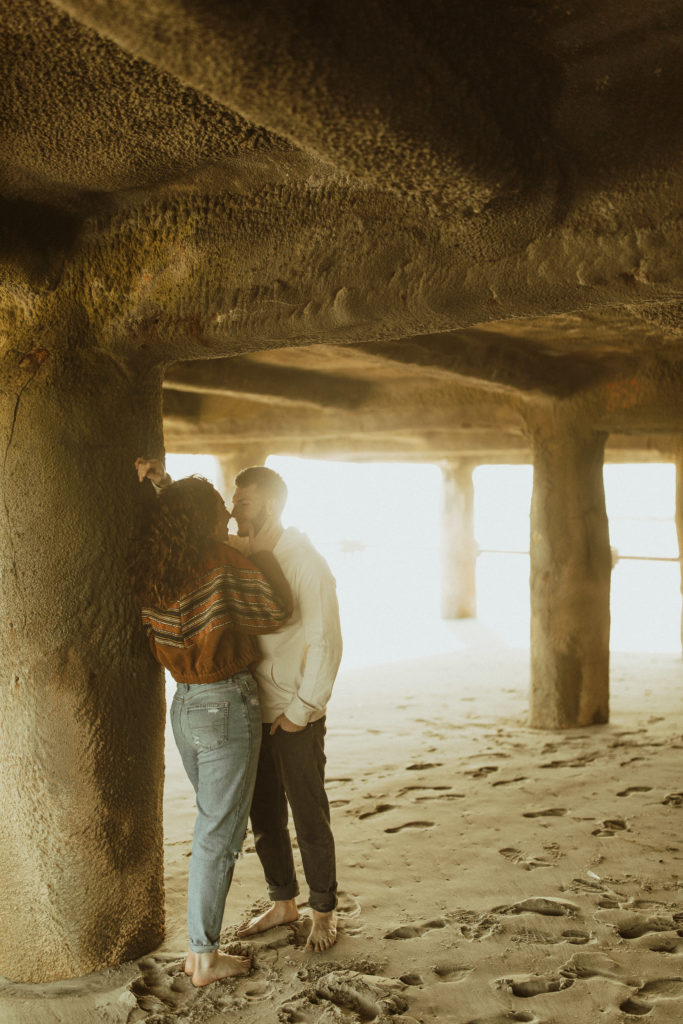 A couples photoshoot at the beach underneath the pier