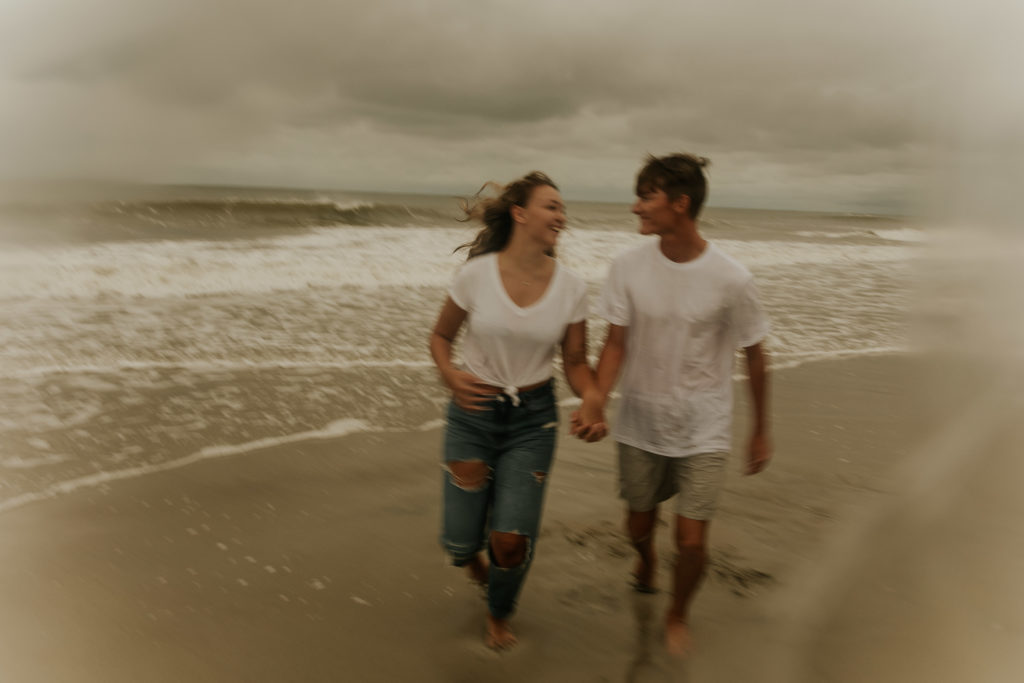 A north carolina couple running on the ocean isle beach during their engagement photoshoot