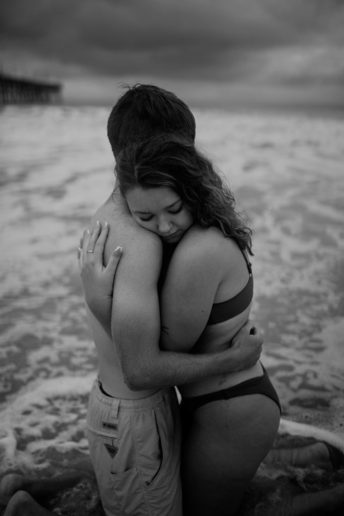 A north carolina couple hugging on the ocean isle beach during their engagement photoshoot