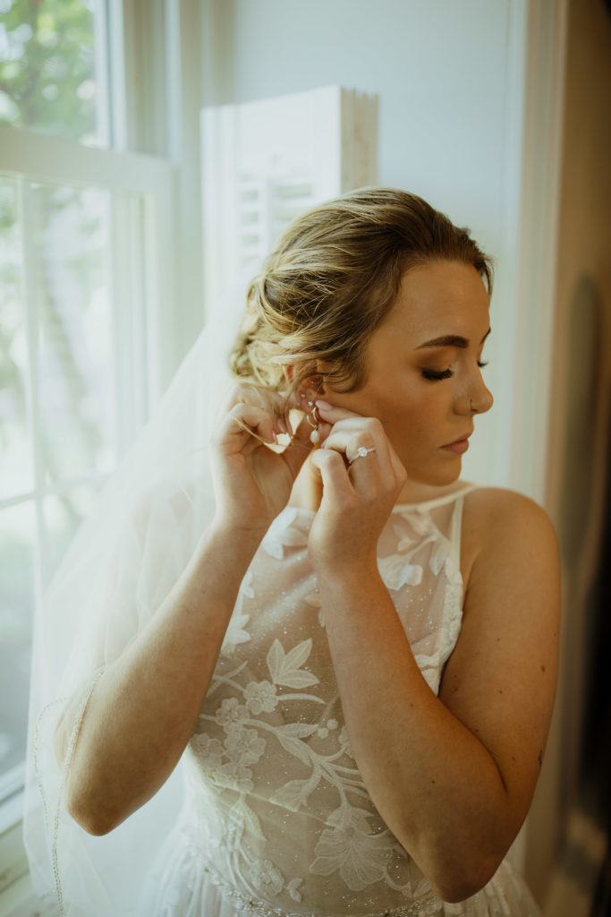The bride putting on her earrings on her wedding day