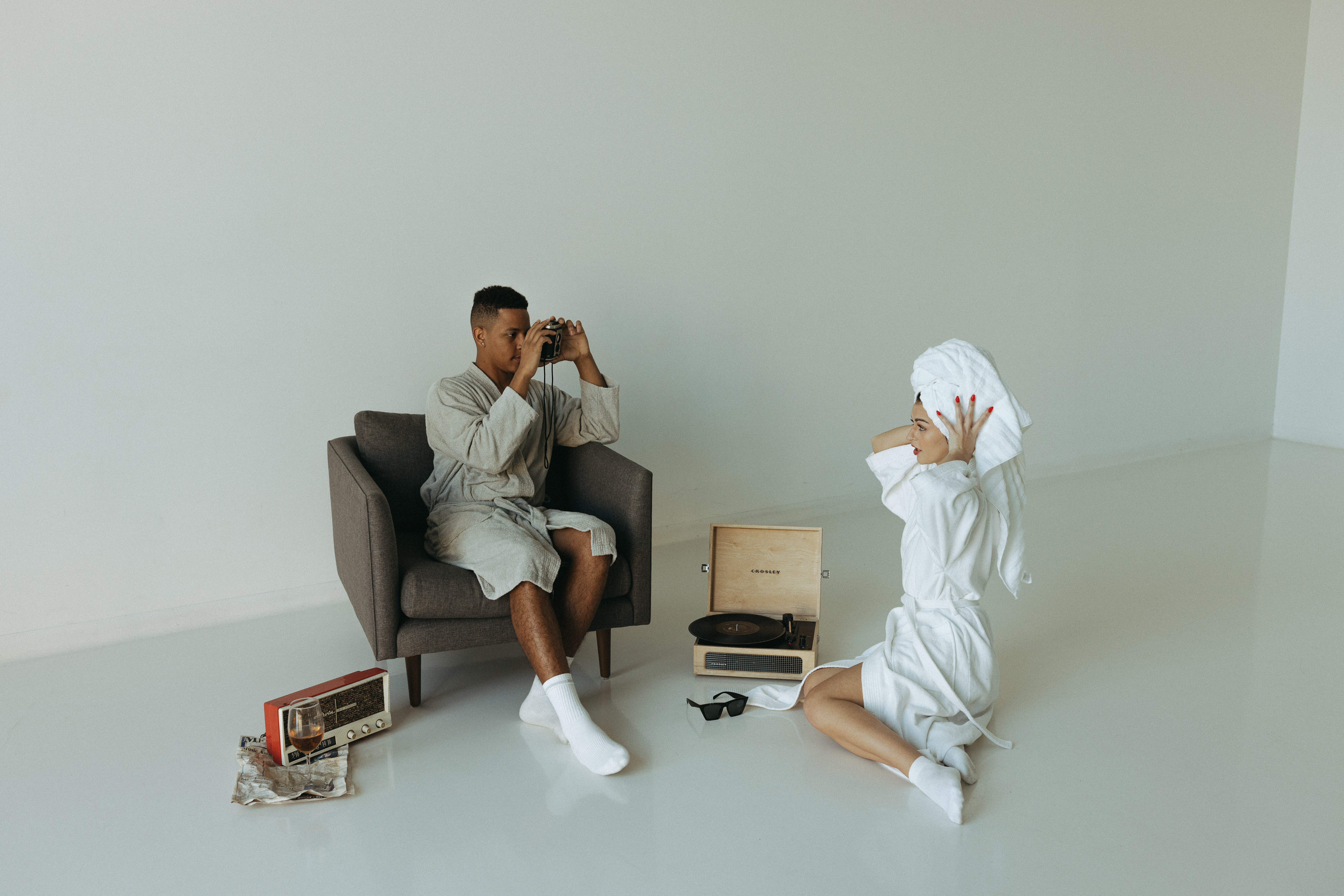 A couple in robes relaxing on a chair and listening to music from an old record player