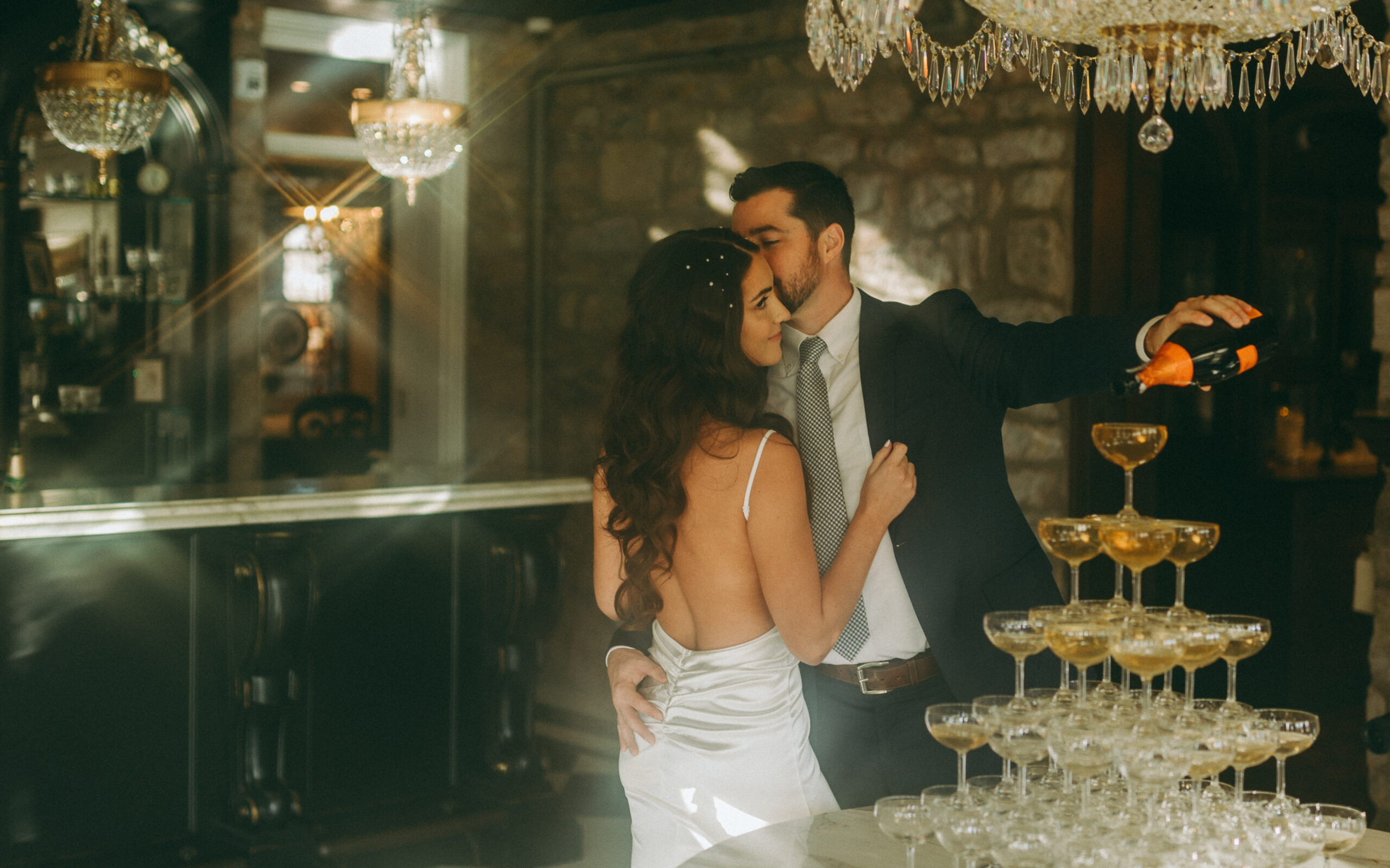 A bride and groom pouring champagne onto their champagne tower at their Mansion wedding